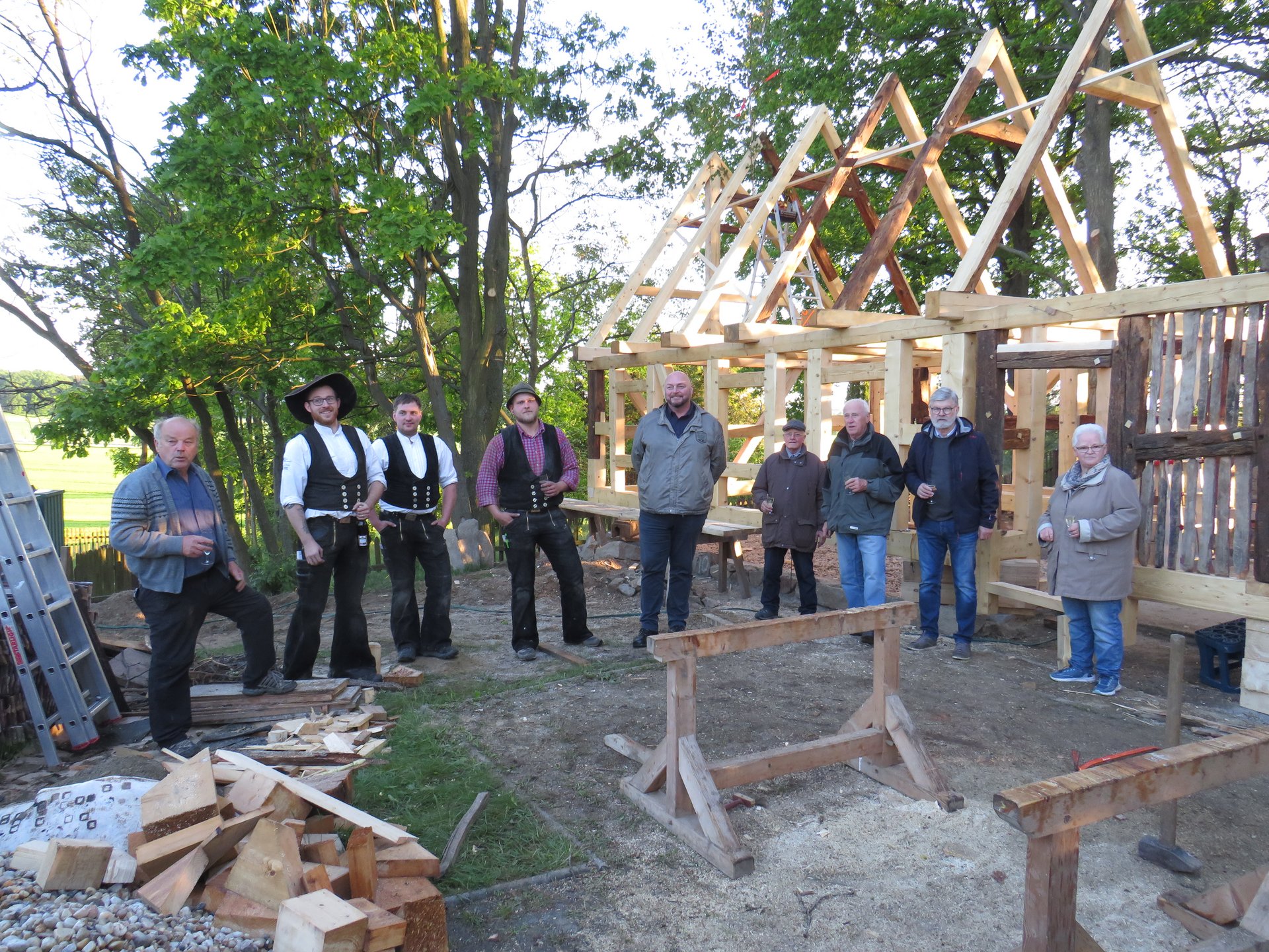 Gruppe von Männern steht vor einem Holz-Fachwerk.