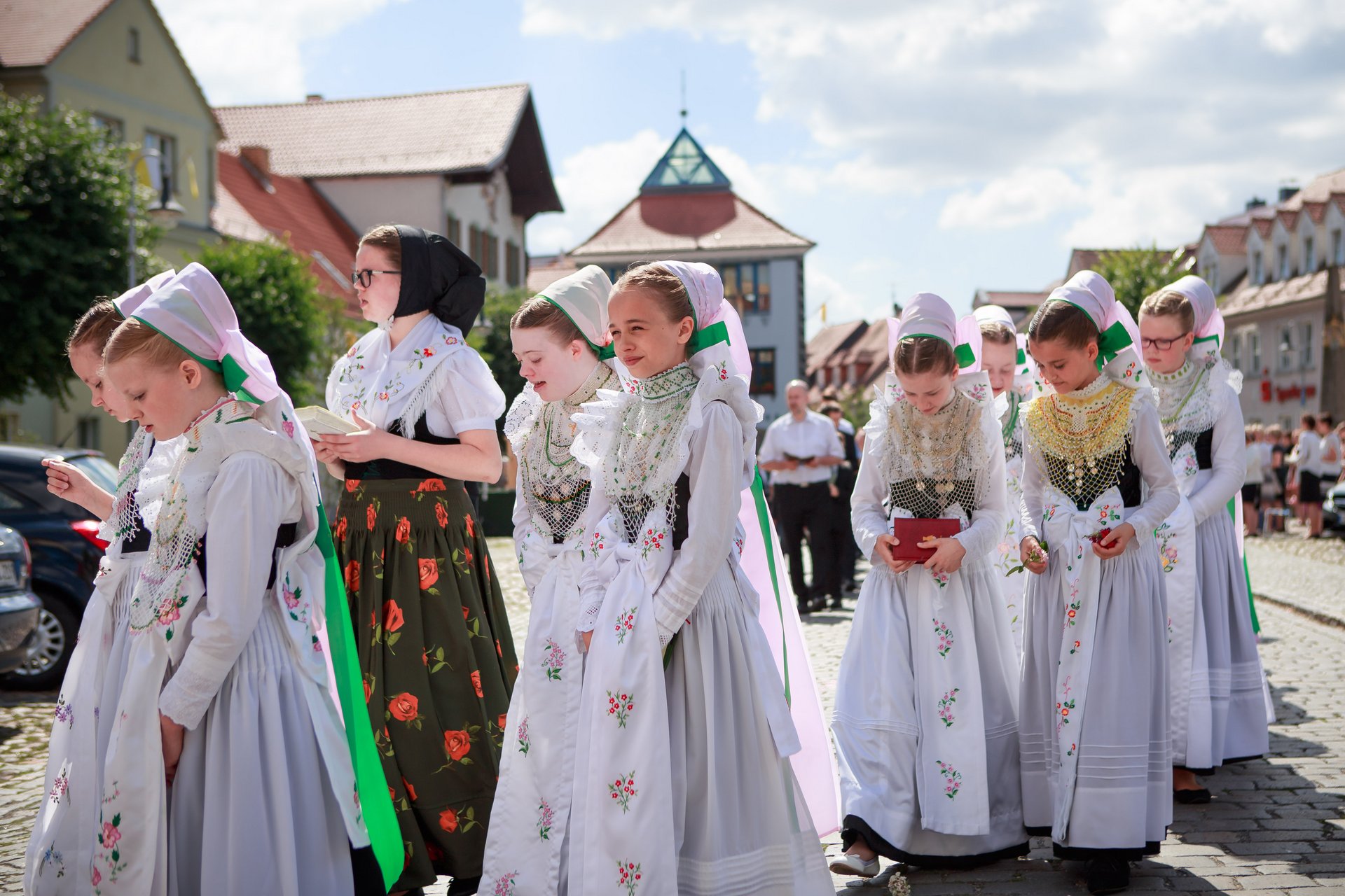 Eine Gruppe von jungen Frauen in Tracht läuft durch einen Ort.